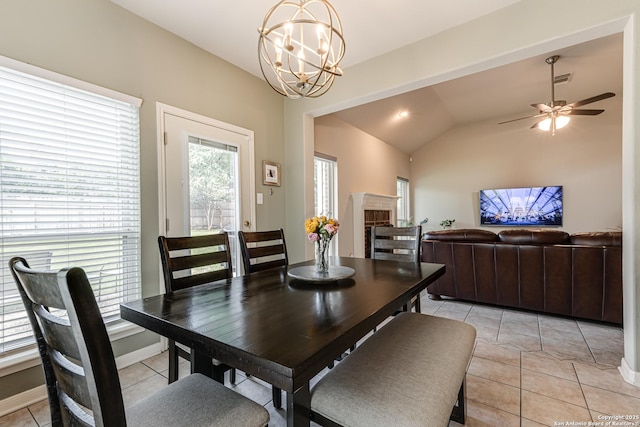 tiled dining area featuring ceiling fan with notable chandelier and vaulted ceiling