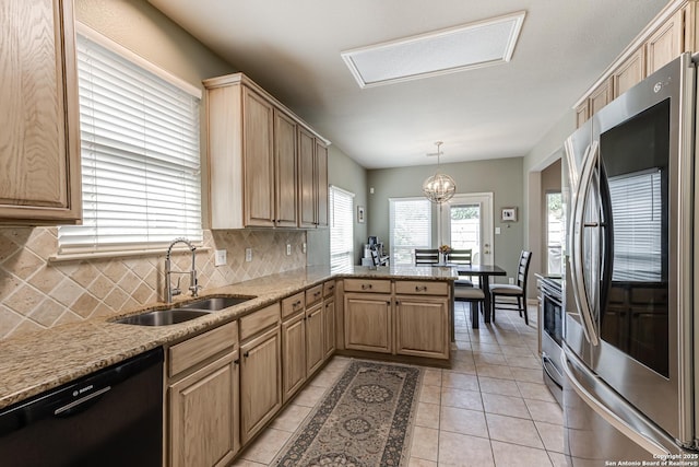 kitchen with stainless steel refrigerator, hanging light fixtures, kitchen peninsula, sink, and black dishwasher