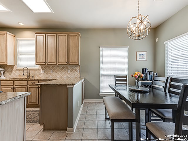 kitchen with pendant lighting, a notable chandelier, light tile patterned floors, and tasteful backsplash