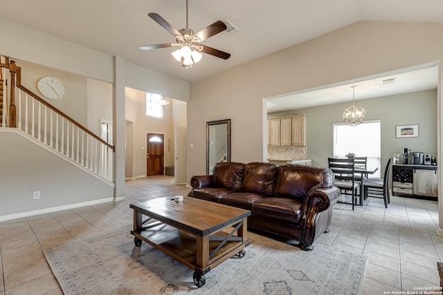 tiled living room featuring ceiling fan with notable chandelier and lofted ceiling