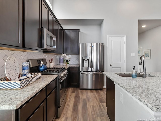 kitchen featuring light stone counters, stainless steel appliances, decorative backsplash, dark hardwood / wood-style flooring, and sink