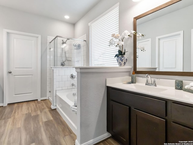 bathroom with wood-type flooring, vanity, and shower with separate bathtub