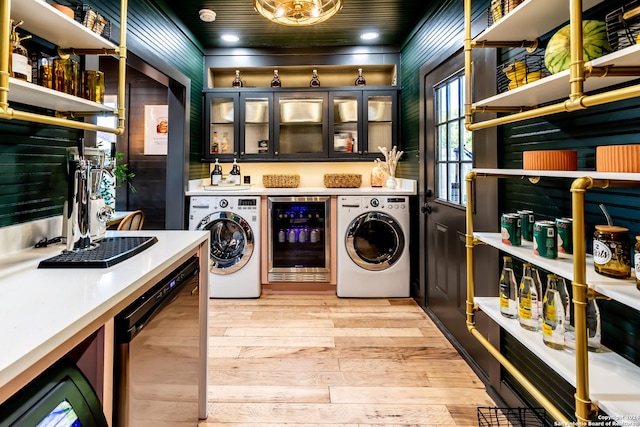 laundry area with light hardwood / wood-style flooring, beverage cooler, and washing machine and dryer