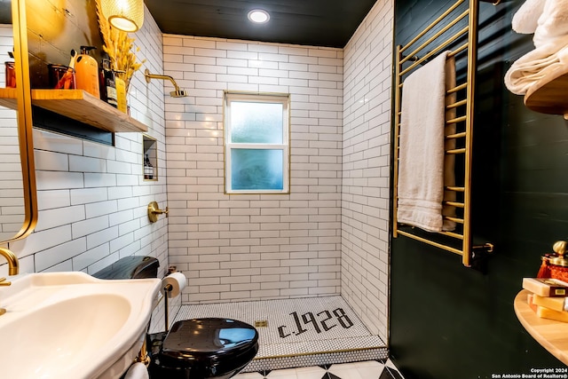 bathroom with toilet, tile patterned flooring, a tile shower, and sink