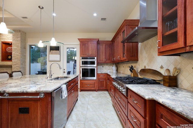 kitchen featuring hanging light fixtures, stainless steel appliances, decorative backsplash, sink, and wall chimney range hood