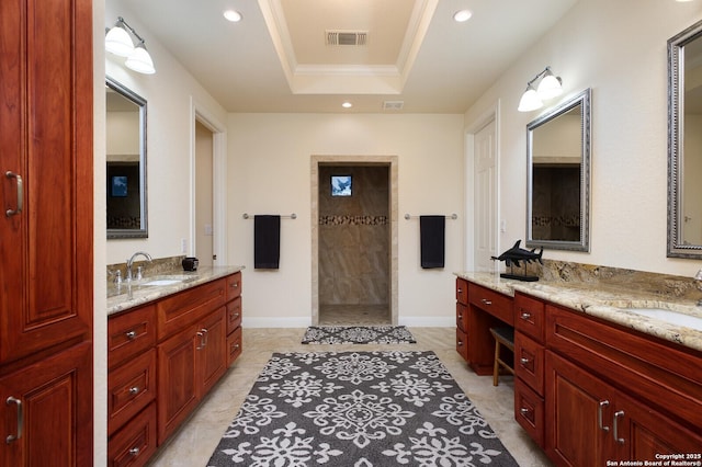 bathroom with a tile shower, vanity, and a tray ceiling