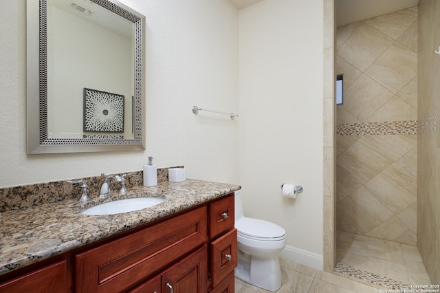 bathroom featuring toilet, tiled shower, tile patterned flooring, and vanity