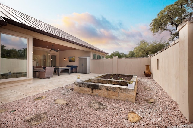 yard at dusk with a patio and ceiling fan