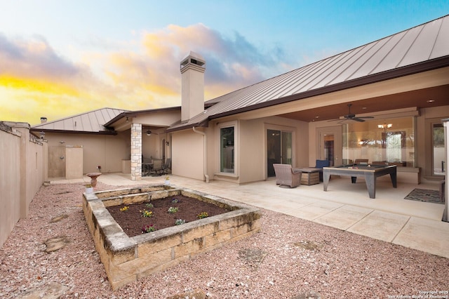 back house at dusk with a patio area, ceiling fan, and an outdoor living space