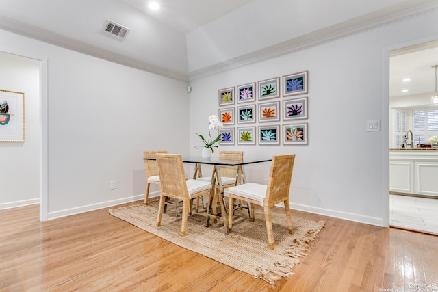 dining room featuring light hardwood / wood-style floors, crown molding, and sink