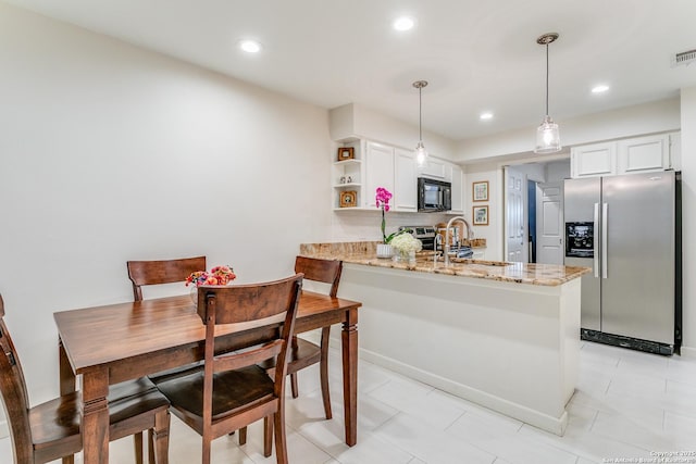 kitchen with stainless steel appliances, white cabinetry, kitchen peninsula, and pendant lighting