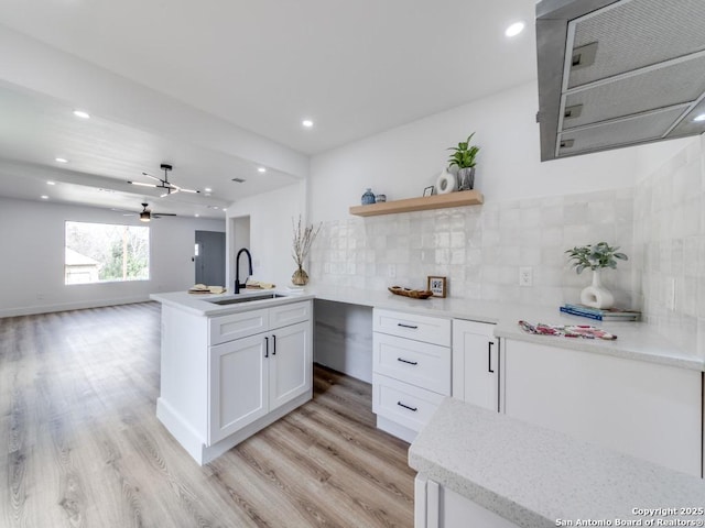 kitchen with light wood-type flooring, ceiling fan, sink, white cabinetry, and tasteful backsplash