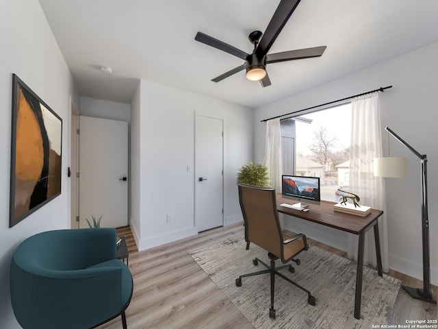 office with light wood-type flooring and ceiling fan