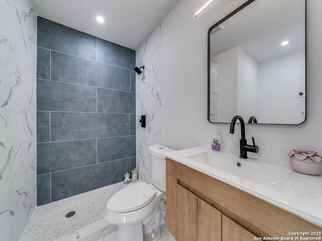 bathroom with a tile shower, vanity, and toilet