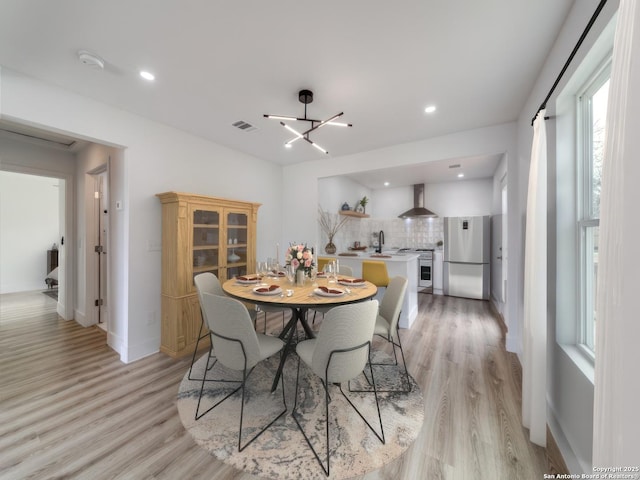 dining area featuring a healthy amount of sunlight, a notable chandelier, light hardwood / wood-style flooring, and sink