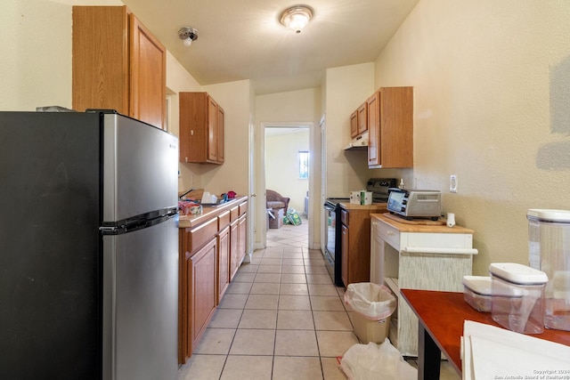 kitchen with light tile patterned floors, stainless steel fridge, and black range with electric stovetop