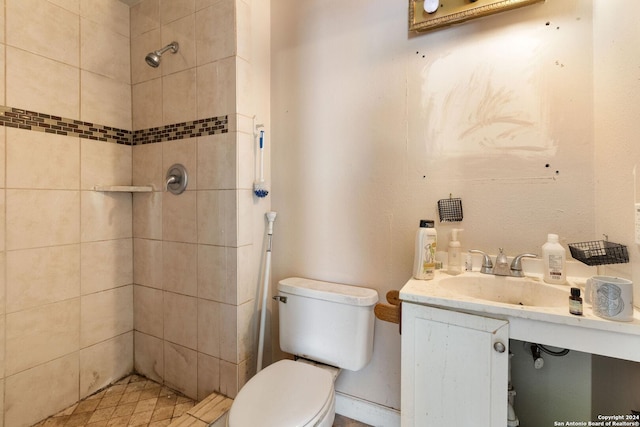 bathroom with sink, a tile shower, and toilet