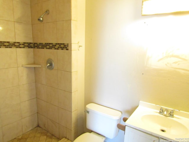 bathroom featuring toilet, a tile shower, and vanity