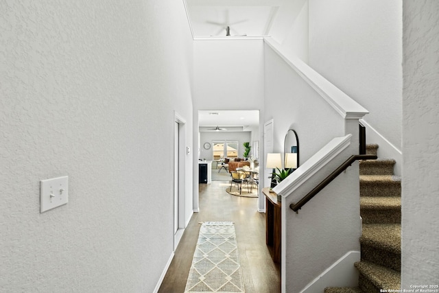 staircase featuring a towering ceiling, ceiling fan, and hardwood / wood-style floors