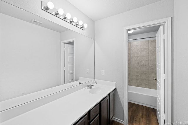 bathroom with wood-type flooring, vanity, and tiled shower / bath combo