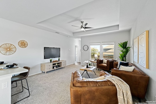 living room with carpet floors, ceiling fan, and a tray ceiling