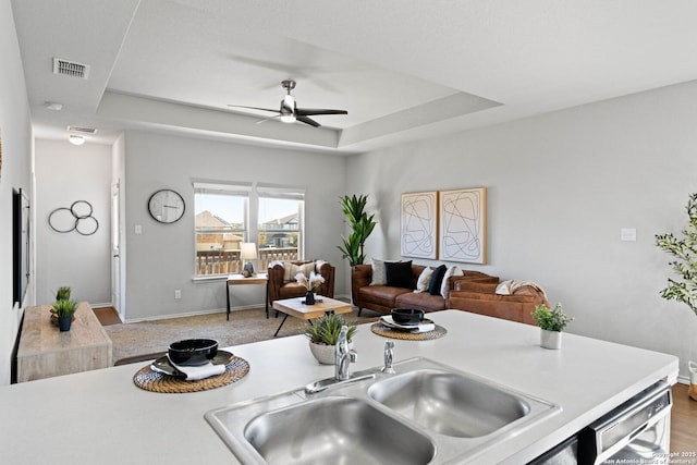 kitchen featuring sink, dishwasher, ceiling fan, and a tray ceiling