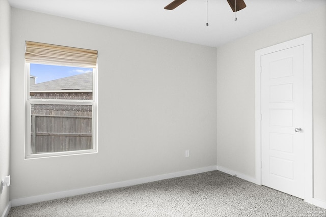 carpeted empty room featuring ceiling fan and baseboards