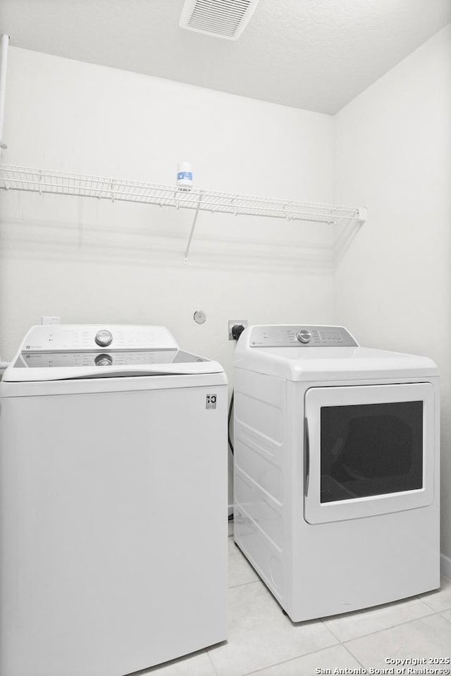 laundry room with light tile patterned floors, laundry area, visible vents, and separate washer and dryer