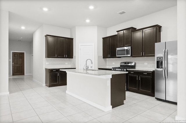 kitchen featuring a center island with sink, appliances with stainless steel finishes, light tile patterned floors, sink, and backsplash