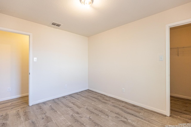 unfurnished bedroom with a closet, light hardwood / wood-style flooring, and a spacious closet