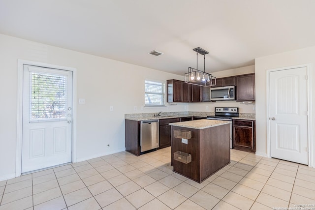 kitchen featuring hanging light fixtures, stainless steel appliances, a kitchen island, dark brown cabinetry, and sink