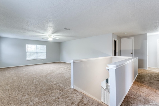 carpeted empty room featuring a textured ceiling and ceiling fan