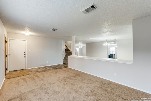 carpeted empty room featuring a textured ceiling and a notable chandelier