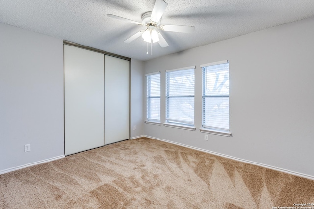 unfurnished bedroom with ceiling fan, a textured ceiling, and light carpet