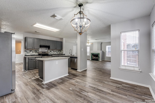 kitchen featuring ceiling fan with notable chandelier, appliances with stainless steel finishes, decorative light fixtures, tasteful backsplash, and gray cabinets