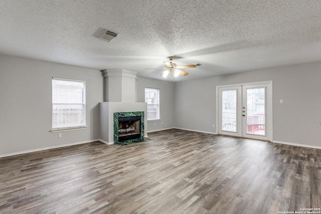 unfurnished living room with ceiling fan, french doors, plenty of natural light, and a premium fireplace