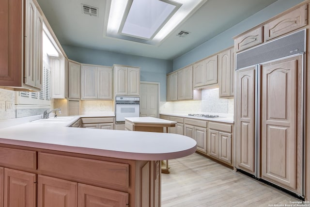 kitchen featuring white appliances, kitchen peninsula, decorative backsplash, and sink