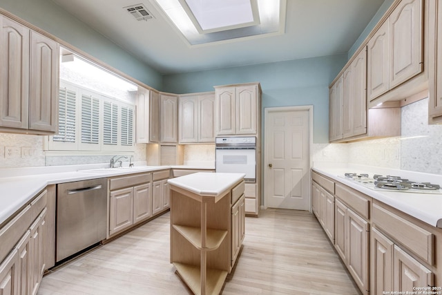 kitchen featuring white appliances, a center island, light hardwood / wood-style floors, light brown cabinets, and sink