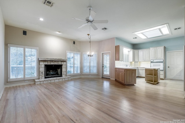 kitchen featuring a center island, decorative light fixtures, light hardwood / wood-style floors, oven, and ceiling fan with notable chandelier