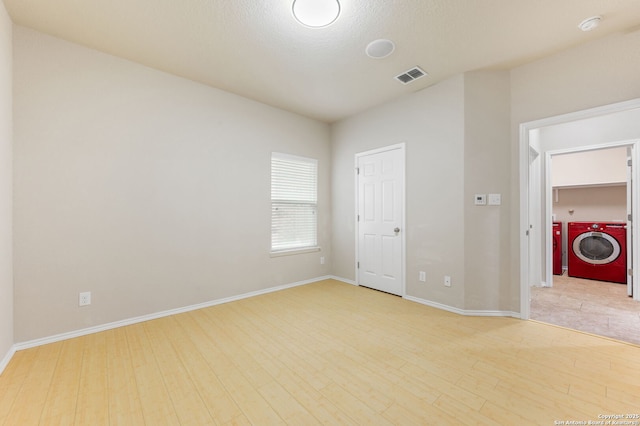 empty room featuring hardwood / wood-style flooring, a textured ceiling, and washing machine and dryer