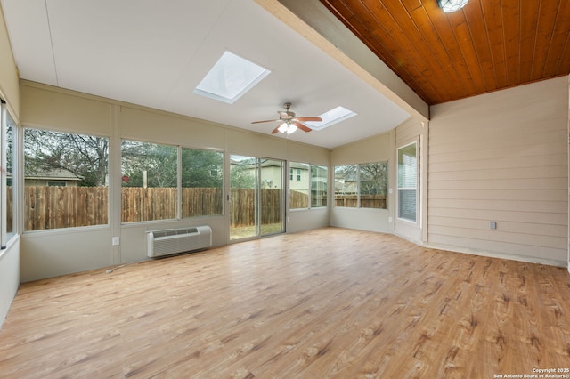 unfurnished sunroom with an AC wall unit, lofted ceiling with skylight, ceiling fan, and wood ceiling