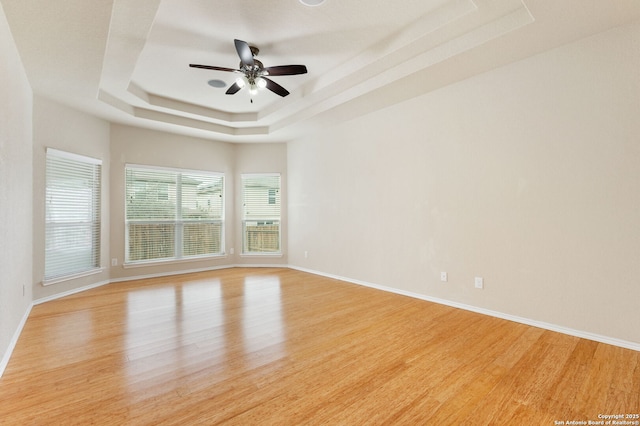 spare room with ceiling fan, a tray ceiling, and light hardwood / wood-style floors