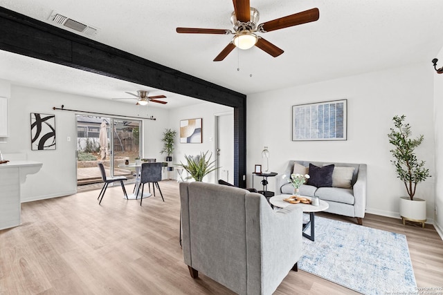 living room with light hardwood / wood-style floors, ceiling fan, and a textured ceiling