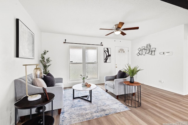 living room featuring hardwood / wood-style flooring, a textured ceiling, and ceiling fan