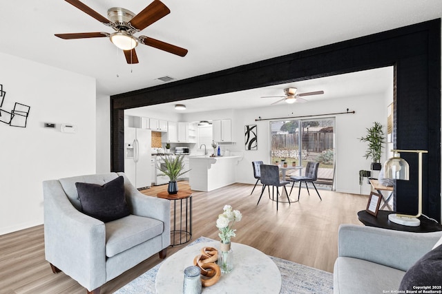 living room featuring light hardwood / wood-style floors, ceiling fan, and sink