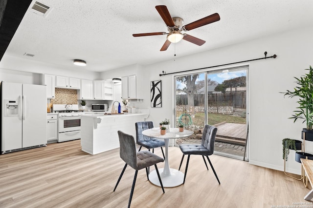 dining room with ceiling fan, light hardwood / wood-style flooring, sink, and a textured ceiling