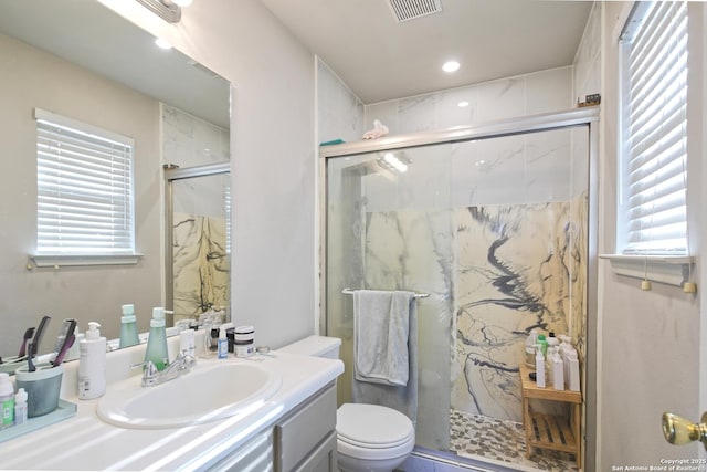 bathroom featuring a shower with door, vanity, and toilet