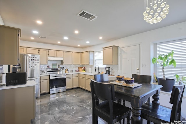 kitchen featuring a chandelier, appliances with stainless steel finishes, light brown cabinetry, sink, and decorative light fixtures