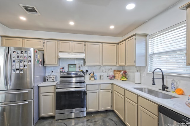 kitchen featuring appliances with stainless steel finishes, cream cabinetry, tasteful backsplash, and sink