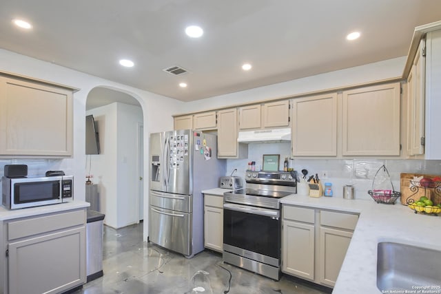 kitchen featuring sink, backsplash, cream cabinetry, and appliances with stainless steel finishes